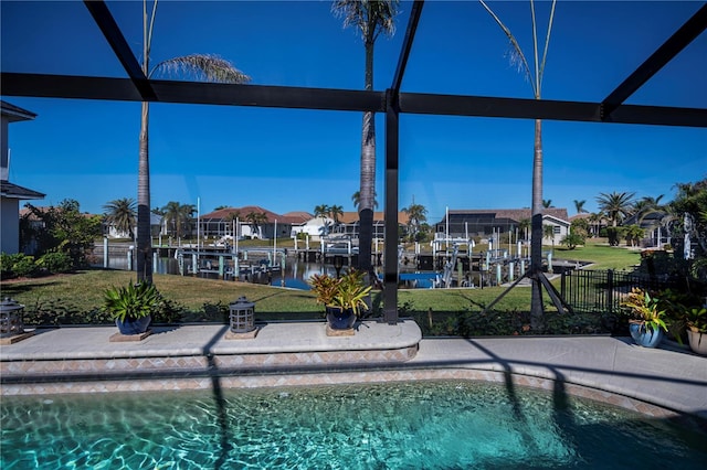 view of pool with a lanai, a lawn, and a water view