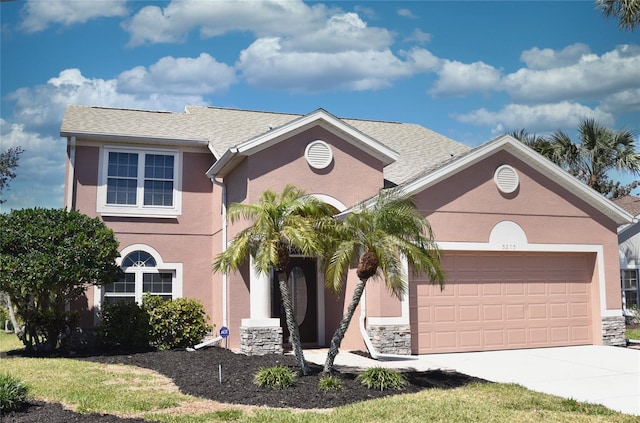 view of front of house featuring stone siding, a garage, driveway, and stucco siding