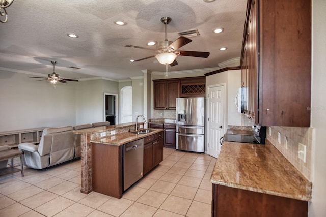 kitchen with a sink, light tile patterned floors, a kitchen island with sink, and stainless steel appliances