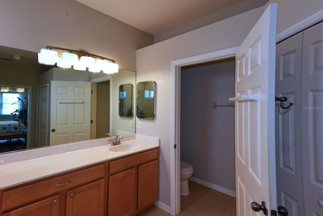 bathroom featuring vanity, baseboards, ensuite bath, tile patterned floors, and toilet