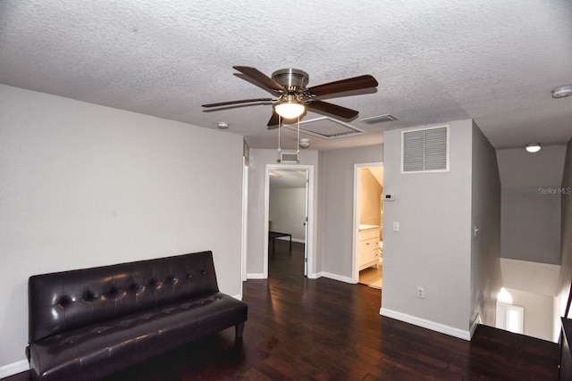 living area with visible vents, a textured ceiling, baseboards, and wood finished floors