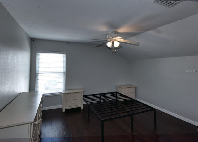 unfurnished bedroom featuring visible vents, baseboards, lofted ceiling, dark wood-style floors, and a textured ceiling