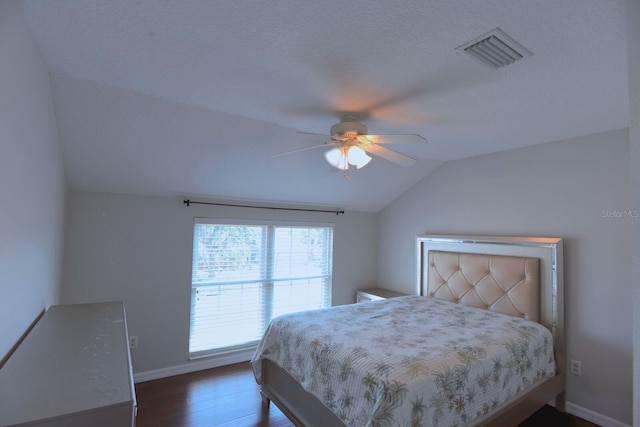 bedroom with visible vents, a ceiling fan, wood finished floors, baseboards, and lofted ceiling