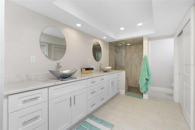 bathroom featuring a tile shower, vanity, a tray ceiling, and toilet