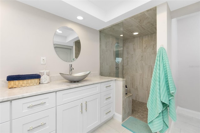 bathroom with tiled shower, vanity, and tile patterned flooring