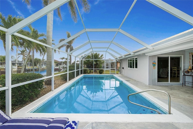 view of pool with a patio area, a water view, and glass enclosure