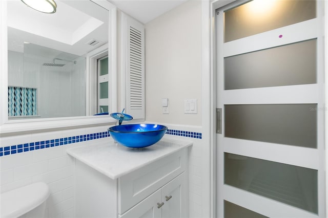 bathroom with vanity, toilet, and tile walls