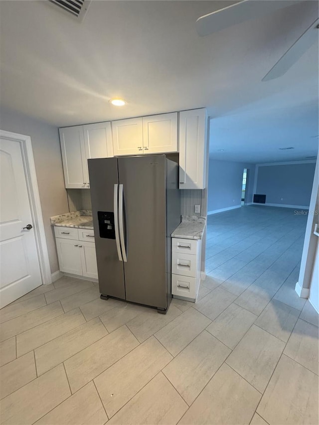 kitchen with white cabinetry, stainless steel fridge with ice dispenser, light stone counters, and decorative backsplash