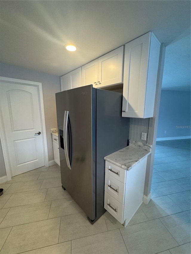 kitchen featuring white cabinetry, decorative backsplash, light stone countertops, and stainless steel refrigerator with ice dispenser