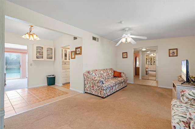 carpeted living room with ceiling fan with notable chandelier