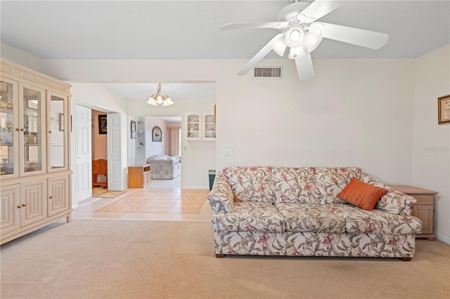 carpeted living room featuring ceiling fan with notable chandelier