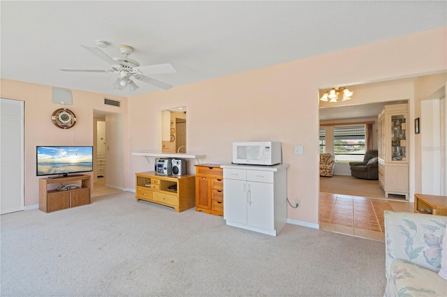 carpeted living room featuring ceiling fan with notable chandelier