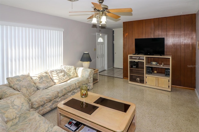 living room with ceiling fan and wood walls