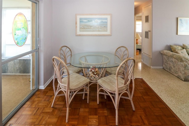 dining space featuring dark parquet flooring