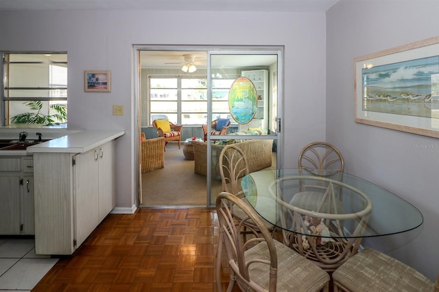 dining space with ceiling fan, dark parquet floors, and sink