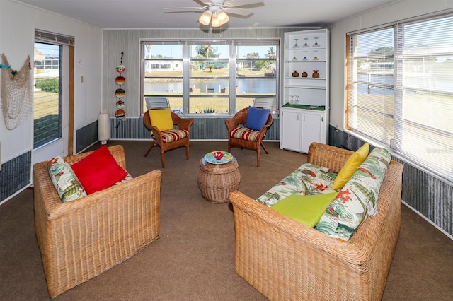 sunroom / solarium featuring ceiling fan and a water view