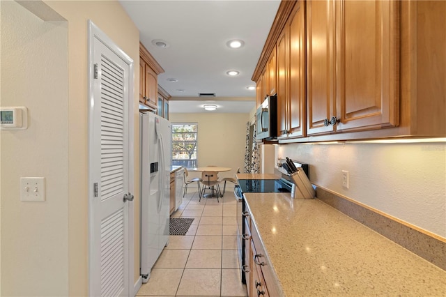 kitchen with light stone countertops, appliances with stainless steel finishes, and light tile patterned floors