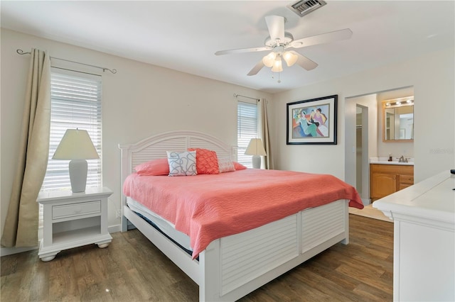 bedroom with connected bathroom, ceiling fan, and dark wood-type flooring