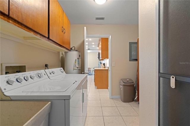 laundry area featuring washing machine and dryer, water heater, light tile patterned floors, and cabinets