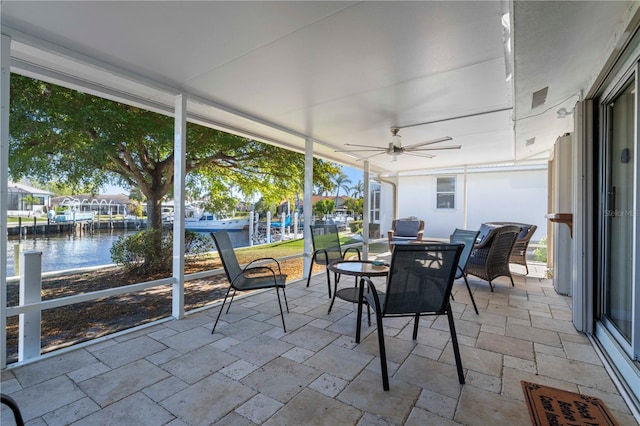 sunroom / solarium with ceiling fan and a water view