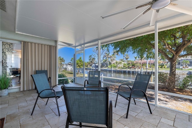 sunroom with ceiling fan and a water view