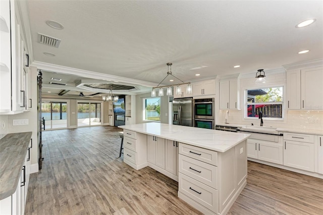 kitchen featuring appliances with stainless steel finishes, light hardwood / wood-style flooring, white cabinetry, and a kitchen island