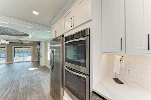 kitchen featuring stainless steel appliances, decorative backsplash, white cabinetry, and light stone countertops