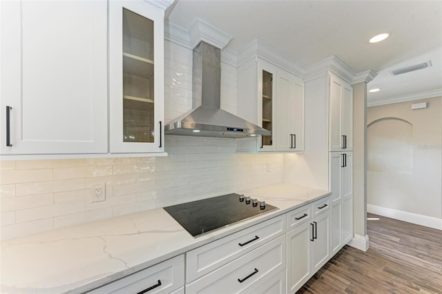 kitchen featuring white cabinets, wall chimney exhaust hood, dark hardwood / wood-style floors, black electric cooktop, and light stone countertops