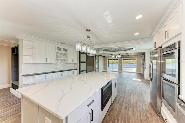 kitchen with stainless steel appliances, white cabinetry, hanging light fixtures, and a center island