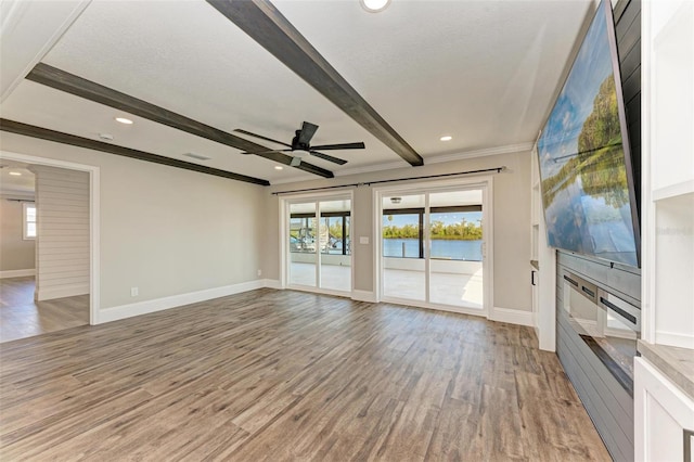 unfurnished living room featuring a textured ceiling, light wood-type flooring, ceiling fan, crown molding, and beam ceiling