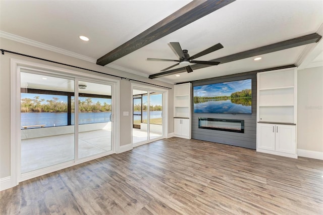 unfurnished living room featuring light hardwood / wood-style floors, a water view, ceiling fan, a fireplace, and built in features