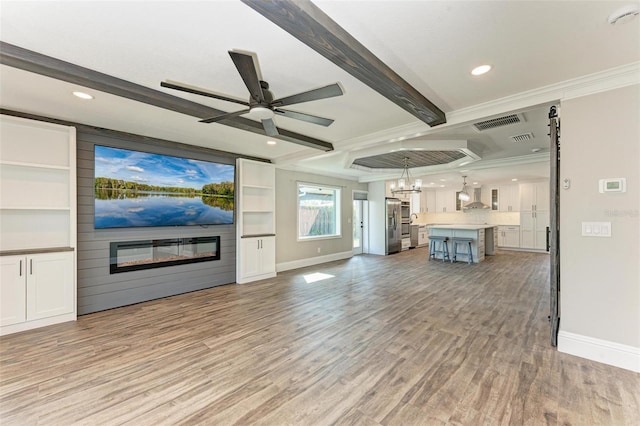 unfurnished living room featuring ceiling fan with notable chandelier, light wood-type flooring, beamed ceiling, and a fireplace