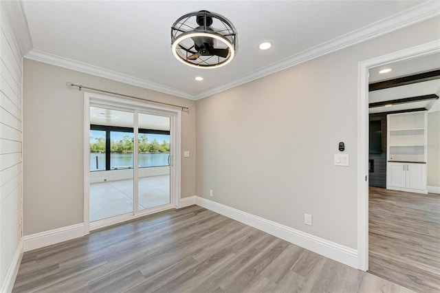 empty room featuring ornamental molding, light wood-type flooring, and a water view