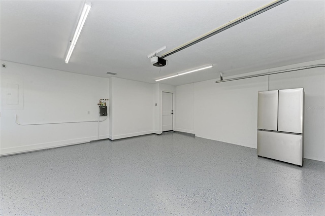 garage featuring stainless steel fridge and a garage door opener