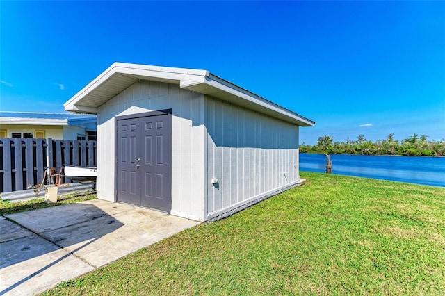 view of outbuilding featuring a water view and a lawn