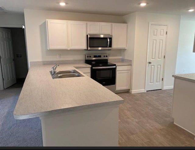 kitchen with kitchen peninsula, light wood-type flooring, stainless steel appliances, sink, and white cabinetry