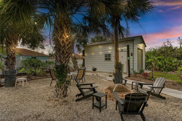 back house at dusk with an outdoor fire pit and an outdoor structure