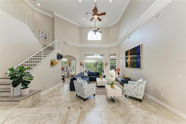 living room with ceiling fan, ornamental molding, and a high ceiling