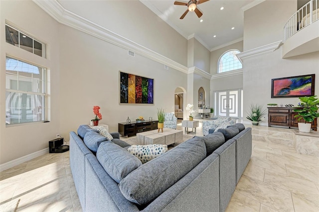 living room featuring ceiling fan, a towering ceiling, and crown molding