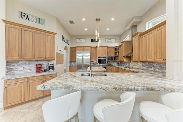 kitchen with appliances with stainless steel finishes, backsplash, a breakfast bar, sink, and decorative light fixtures