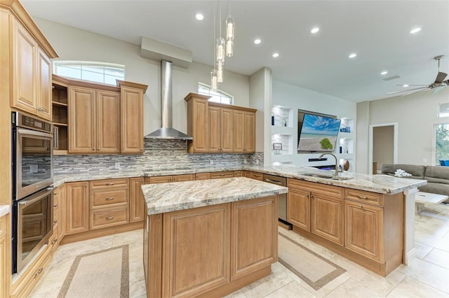 kitchen featuring kitchen peninsula, double oven, sink, wall chimney range hood, and decorative light fixtures