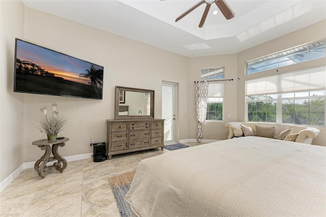 bedroom featuring ceiling fan, a raised ceiling, and light tile patterned floors