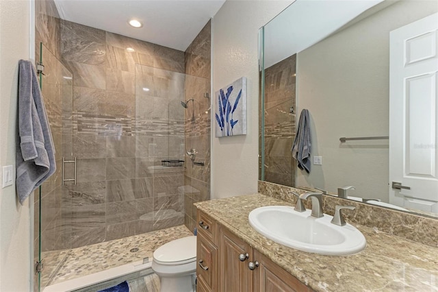 bathroom featuring vanity, toilet, and a shower with shower door