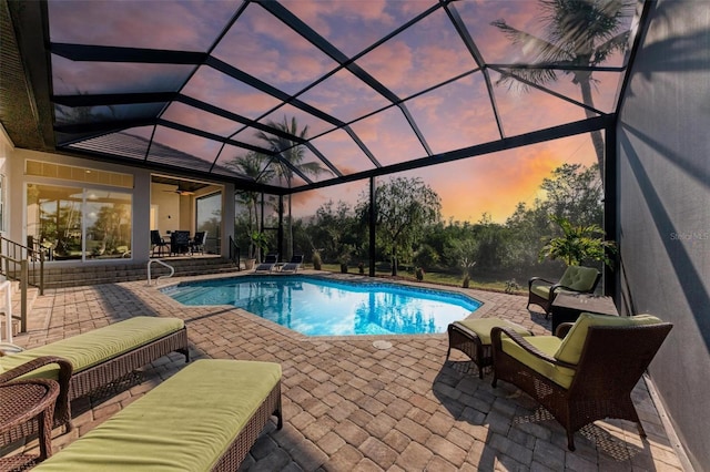 pool at dusk with outdoor lounge area, a lanai, and a patio