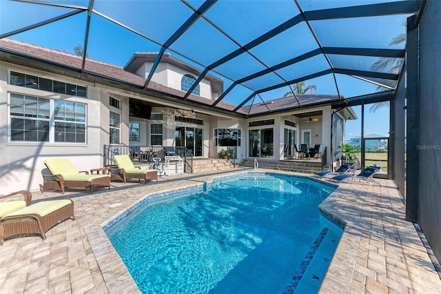 view of swimming pool featuring ceiling fan, a lanai, and a patio