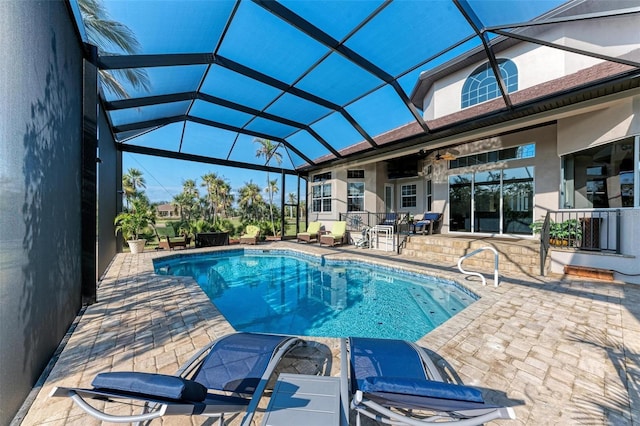 view of pool featuring glass enclosure, ceiling fan, and a patio area