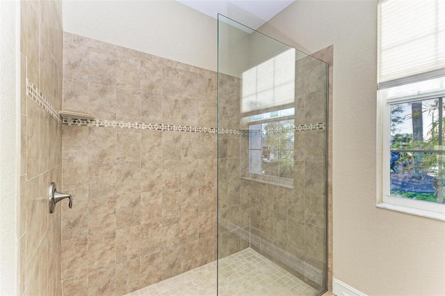 bathroom featuring a tile shower and a healthy amount of sunlight