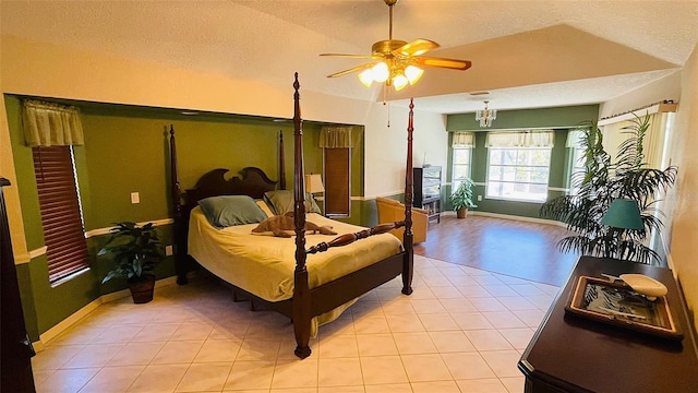 bedroom featuring ceiling fan, light tile patterned floors, a textured ceiling, and lofted ceiling