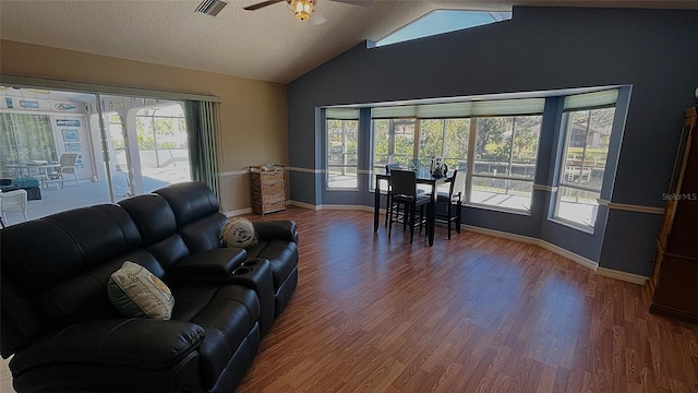 living room with ceiling fan, vaulted ceiling, a textured ceiling, and hardwood / wood-style floors