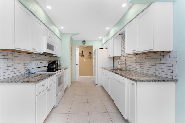 kitchen featuring dark stone countertops, white cabinetry, sink, and white appliances